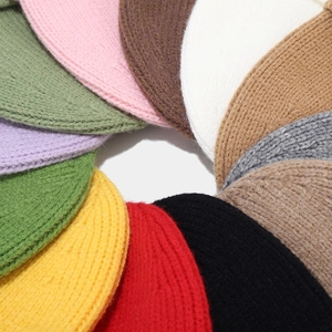 Various colors of chunky knit beanies displayed in a circular stack for winter warmth