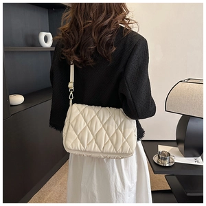 Detail showing white quilted crossbody bag with diamond pattern on a female model