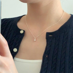Selfie view of a minimalist silver smiley face pendant necklace worn on the collarbone
