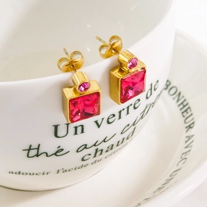 Square red ruby zircon titanium steel earrings in gold finish on white ceramic cup