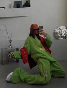 Detail of green knit lounge set showing yellow logo print and wide-leg jogger pants fit