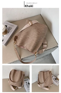 Detail view of khaki faux crocodile leather bucket bag with wide woven strap and metal hardware