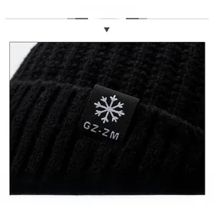 Détail du bonnet en maille noire avec écusson carré et broderie de flocon de neige