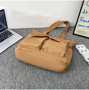 Detail of khaki canvas tote bag with front pockets showing large storage space