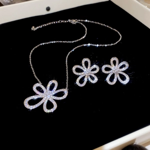 Macro detail of silver flower jewelry set with sparkling rhinestones on black background