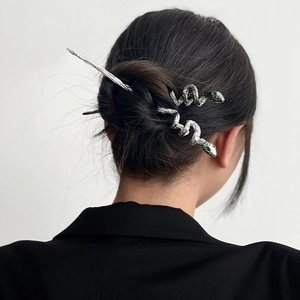 Silver snake hair pin with green eyes shown in a low bun on a model in a black suit