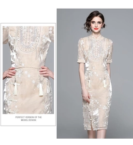 Detail of floral lace embroidery and tassel accents on a champagne modern qipao dress