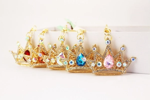 Close-up of five colorful crystal crown keychains with gold plating and rhinestones