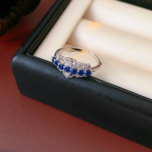 Détail macro d'une bague ouverte en dentelle argentée avec zircons bleu foncé et cristaux