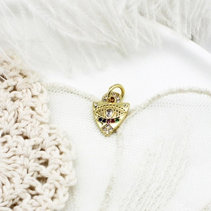 Macro shot of gold evil eye pendant with colorful cubic zirconia on white lace background