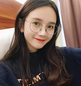 Close-up of lightweight round metal frame glasses with gold temples on a person