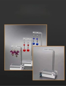 Clear acrylic earring display stand with L-shaped hooks and stable base in macro view