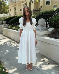 Détail d'une robe blanche à manches bouffantes avec plis à la taille et laçage frontal