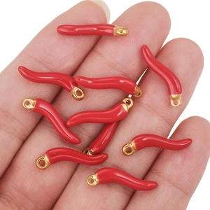 Handheld view of red enamel chili pepper charms with gold metal rings for DIY jewelry