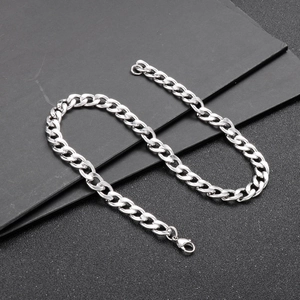 Macro detail of a silver Cuban link chain with a lobster clasp on a dark background