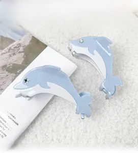 Detail view of light blue dolphin hair clips with rhinestones on soft white background