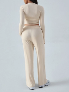 Rear view of beige two-piece yoga set featuring long sleeve crop top and wide leg pants