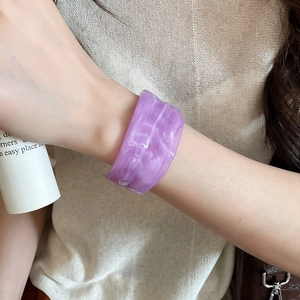 Detail of purple marble acrylic wide cuff bracelet worn with chic minimalist apparel