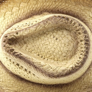 Macro detail of hand-woven straw jazz hat showing tight fiber texture and vintage brown dye