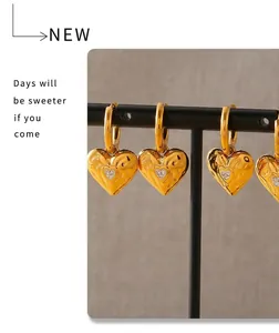 Detail view of gold hammered heart earrings with zircon studs on a black jewelry stand