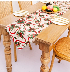 Close-up of Christmas table runner with holly leaf prints and scalloped edges on wood table