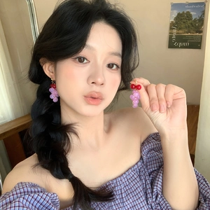 Boucles d'oreilles grappe de raisin en résine avec perles violettes portées par mannequin