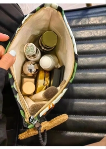 Top view of large canvas makeup bag with tropical pattern being opened by a hand