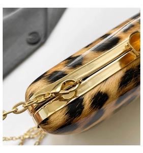 Detailed close-up of the golden metal clasp and chain strap on a leopard print evening bag
