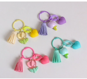 Detail of colorful resin tulip keychains with tassels and heart charms on white background
