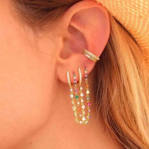 Gros plan détaillé de boucles d'oreilles à franges zircon arc-en-ciel et d'un earcuff