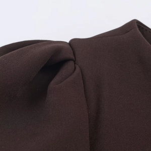 Close-up of dark brown fabric showing pleated knot detail and textured weave quality