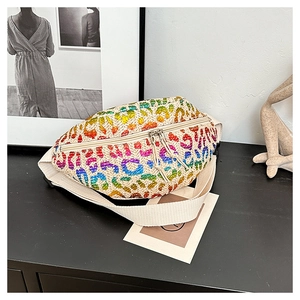 Close-up of woven waist bag featuring rainbow leopard print and dual metal zippers