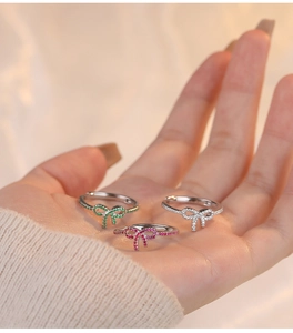 Macro shot of a sparkling silver bow ring with green zircon stones on a woman's finger