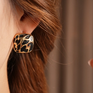 Gros plan d'un mannequin portant des boucles d'oreilles carrées léopard dorées et noires