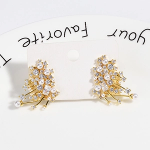Macro shot of branch-shaped gold earrings with white pearls and clear zircons