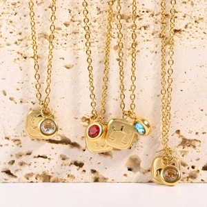 Detail of 18K gold plated necklaces featuring zodiac pendants and colorful birthstones