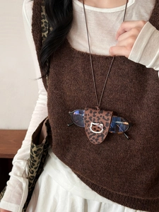 Detail of leopard print leather magnetic cat glasses holder pendant on a model sweater