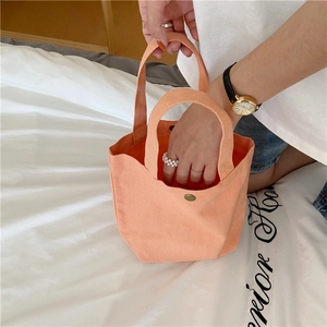 Close-up of orange canvas lunch bag with durable metal snap button and sturdy handles