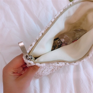 Detail shot of white daisy lace embroidery cosmetic bag with silver zipper and perfume bottle