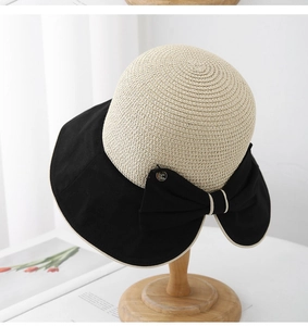 Dettaglio della tesa larga nera e del grande fiocco in tessuto su un cappello di paglia