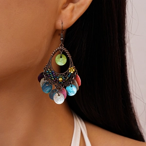 Close-up of Bohemian cutout drop earrings with colorful shell inserts on a female model