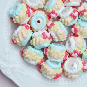 Close-up of DIY resin beads shaped like mini cakes with pink bows and blue icing