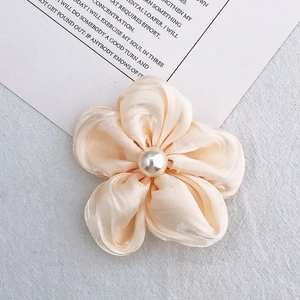 Detailed macro view of an apricot silk flower accessory with a central white pearl bead