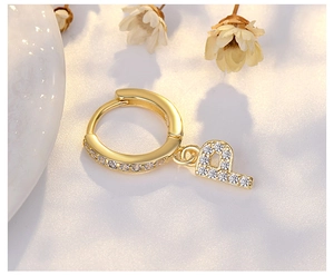 Macro detail of a gold letter P earring with micro-pave crystals and polished finish