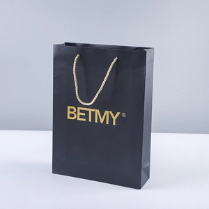 Elegant black paper gift bag with golden woven handles and premium gold logo branding