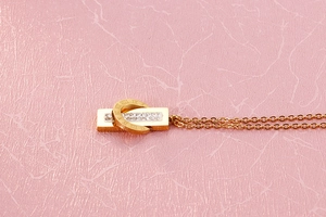 Close-up of golden geometric necklace featuring roman numerals and sparkling rhinestones
