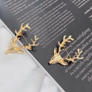 Broche tête de cerf vintage dorée pour costumes, présentée sur un fond de magazine noir