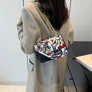 Chic graffiti print square crossbody bag with gold chain strap shown on a model