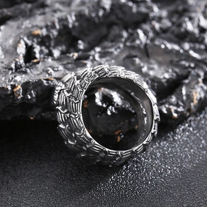 Macro shot of silver python ring with detailed snake scale texture on volcanic rock