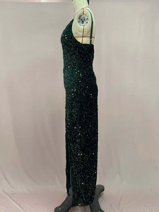 Détail d'une robe de soirée vert foncé à paillettes avec fente latérale et fines bretelles
